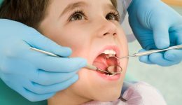 Close-up of little boy opening his mouth wide during inspection of oral cavity